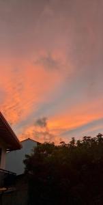 una puesta de sol en el cielo con un edificio y árboles en Imen villa, en Hikkaduwa