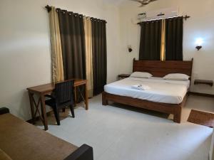 Un dormitorio con una cama, un escritorio y una mesa. en Coastal Suites Apart Hotel ---- 12 minutes walk to beach, en Benaulim