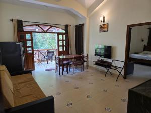Una sala de estar con una mesa y sillas y un televisor. en Coastal Suites Apart Hotel ---- 12 minutes walk to beach, en Benaulim