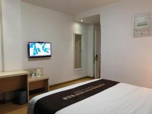 een hotelkamer met een bed en een tv aan de muur bij 7 Days Inn Ningbo Xiangshan Renmin Plaza Branch in Xiangshan