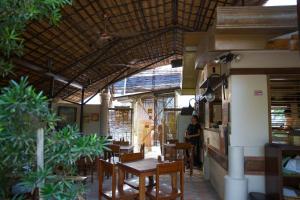 a person standing in a restaurant with tables and chairs at Karancho Beach House in Mactan