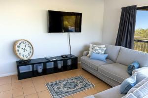 Una sala de estar con un sofá y un reloj en la pared. en Steps from The Strand 2bed 2bath Riveria Retreat Pool & Castle Hill Views in Townsville, en North Ward