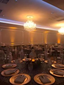 ノーウォークにあるHotel Saddlebackのテーブルと椅子とシャンデリアのあるダイニングルーム