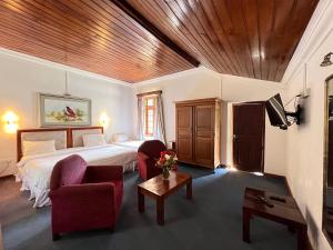 a bedroom with a bed and a couch and a table at Tea Bush Hotel in Nuwara Eliya
