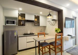 a kitchen with a table and chairs and a refrigerator at BedChambers Luxurious Aparthotel Near Medicity in Gurgaon