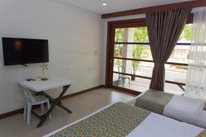 a bedroom with a bed and a desk and a television at Karancho Beach House in Mactan