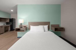 a bedroom with a large white bed and a kitchen at ECHO Suites Extended Stay by Wyndham Johnson City Medical CR in Johnson City +18 photos