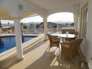Un patio con mesa y sillas y una piscina. en Casa Jolanda, en La Caleta