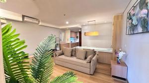 a living room with a couch and a kitchen at The H Tower Rasuna Suites Kuningan Jakarta By Villaloka in Jakarta