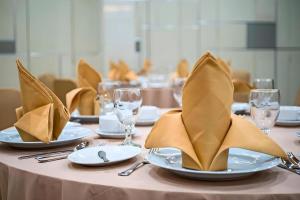 a table with plates and napkins on top at Lotus Hotel Subang in Subang