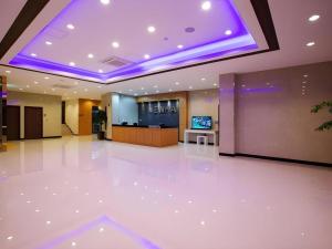 Un vestíbulo con un gran suelo blanco y luces moradas. en Ewha Hotel, en Jeju