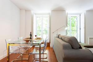 uma sala de estar com uma mesa de vidro e um sofá em ALTIDO Belem Burgundy em Lisboa