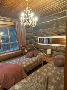 a bedroom with two beds and a chandelier at Villa Karhuntähti in Luosto
