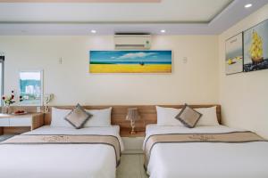 two beds in a hotel room with white walls at Seoul Hotel Cat Ba in Cat Ba