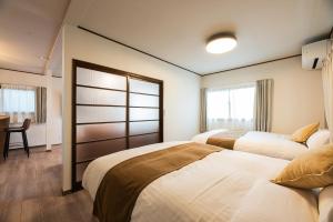 a hotel room with two beds and a desk and a window at Ojanse博多 in Fukuoka