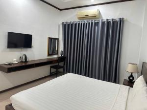 une chambre d'hôtel avec un lit, un bureau et une télévision dans l'établissement Avenue Hotel VangVieng, à Vang Vieng 2 autres photos