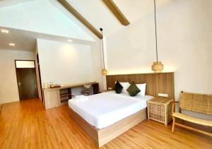 Un dormitorio con una gran cama blanca y una silla. en The Poom Cafe & Resort Khao Yai, en Ban Khanong Phra Klang (1)