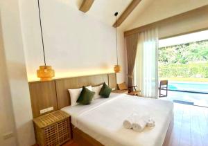 Un dormitorio con una gran cama blanca con toallas. en The Poom Cafe & Resort Khao Yai, en Ban Khanong Phra Klang (1)