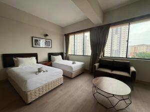 a hotel room with two beds and a couch and a chair at Swing & Pillows - I-City, Shah Alam in Klang +5 photos