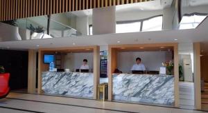 two men standing at a counter in a building at Jinjiang Inn Hotel Tianjin Xinkai Road Branch in Tianjin