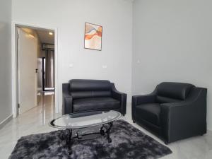 a living room with two black chairs and a coffee table at MARIGOLD APARTMENTS in Salama Park in Lusaka