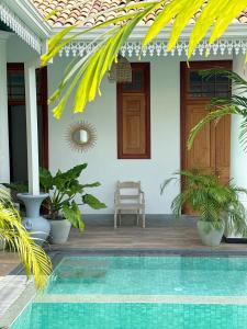 a villa with a swimming pool in front of a house at ISOLA - Surf House in Koggala