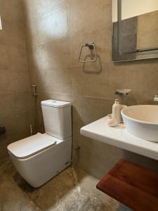 a bathroom with a white toilet and a sink at ISOLA - Surf House in Koggala