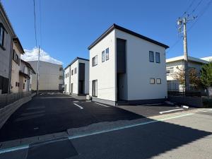 une rangée de bâtiments blancs sur le côté d'une rue dans l'établissement 縁-Takasaki, à Takasaki
