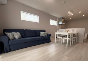 un salon avec un canapé bleu et une table dans l'établissement 縁-Takasaki, à Takasaki