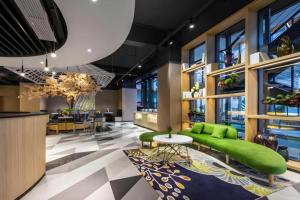 a lobby with a green couch and a table at ibis Styles Kunming Nanping Hotel in Kunming