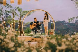 een man en een vrouw staan onder een boog met een gitaar bij Da Lat Cam Ly Hotel in Ấp Kim Thạch