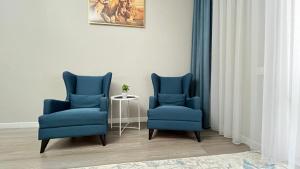 two blue chairs and a table in a room at Athletic City, 1-Room Apartments in Taldykolʼ