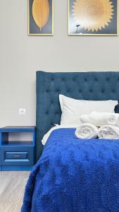 a bedroom with a blue bed with a blue headboard at Athletic City, 1-Room Apartments in Taldykolʼ