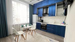 a kitchen with blue cabinets and a table and chairs at Athletic City, 1-Room Apartments in Taldykolʼ +10 photos