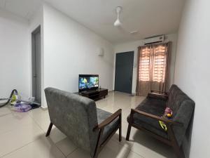 un salon avec deux fauteuils et une télévision dans l'établissement Consolatio Near Teluk Senangin, à Lumut