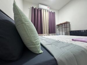 un lit avec un oreiller dessus et des rideaux violets dans l'établissement Consolatio Near Teluk Senangin, à Lumut