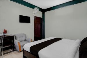 a bedroom with a bed and a chair and a television at Townhouse Howell Crossway Shillong Formerly Laban Guest House in Shillong