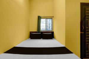 Un dormitorio con una cama con paredes amarillas y una ventana. en Hotel O Madhyamgram Railway Junction Formerly Dreamland, en Dohāri