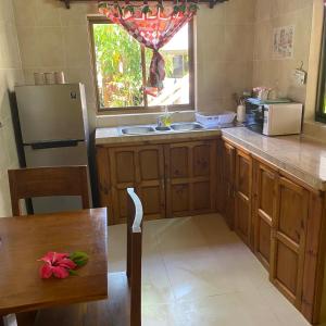 a kitchen with wooden cabinets and a sink and a window at Linsen Selfcatering Apartments in La Digue