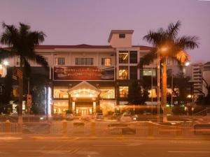a large building with palm trees in front of it at Dong Cheng Hotel in Shunde