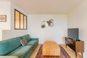 ein Wohnzimmer mit einer grünen Couch und einem Tisch in der Unterkunft Charming apartment 2ch 4p parking and balcony in La Madeleine