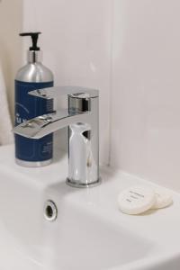 a sink with a faucet and a bottle of soap at Chic 2-Bed, 2 Bath Apt in City Centre Sleeps 6, Free Secure Parking in Belfast
