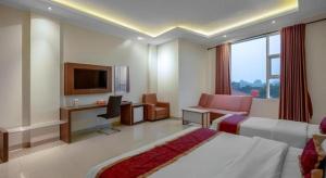 a hotel room with a bed and a desk and a tv at Raffleshom Hotel in Bandung
