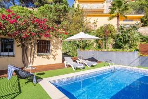 a swimming pool with two chairs and an umbrella at Lloret · Villa Gamené piscina y mar in Lloret de Mar
