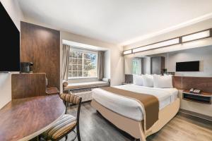 a hotel room with a bed and a desk and a window at Microtel Inn & Suites by Wyndham Pearl River/Slidell in Pearl River