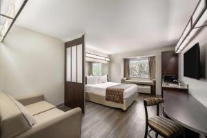 a hotel room with a bed and a couch at Microtel Inn & Suites by Wyndham Pearl River/Slidell in Pearl River