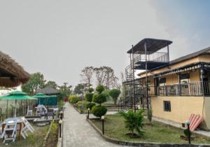 a resort with a building and a table and chairs at Hotel RaptiRiverview in Khargauli