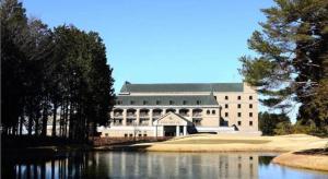 een groot gebouw met een meer ervoor bij HOTEL WINDSOR in Nakatsugawa