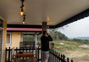 a man standing on the porch of a house at Hotel RaptiRiverview in Khargauli