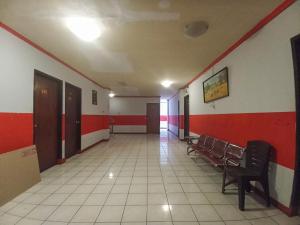 an empty hallway with chairs and red and white walls at RedDoorz near Sam Ratulangi Manado in Manado